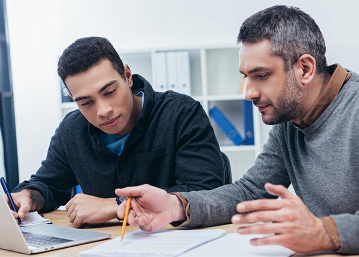 Two male employees work together to find a solution.