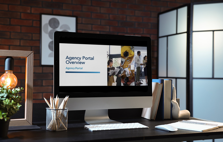 Computer with a video on a screen in a room with a brick wall.