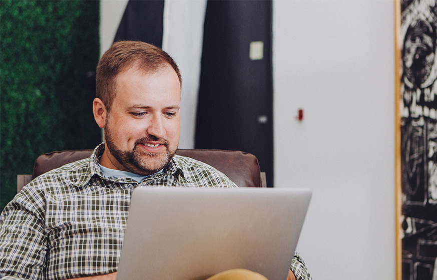 A man working on a laptop while sitting on a couch.