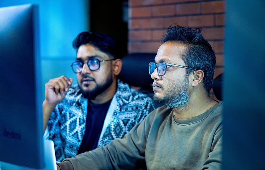 Two men reviewing something on a computer.